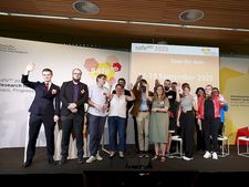 Group picture at safeND 2023, showing around 20 people on a stage in front of posters of the event