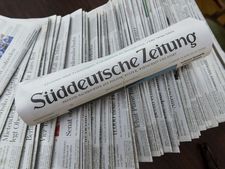 Eine gerollte Ausgabe der Süddeutschen Zeitung liegt über ausgebreiteten Zeitungen.